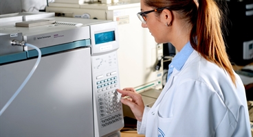 Female laboratory technician adjusts the Gas Chromatograph